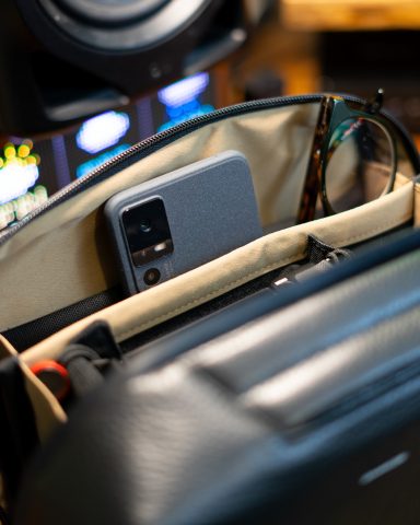 A smartphone and sunglasses inside a bag, with blurred background elements.